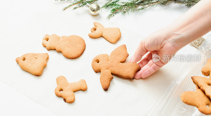 Womans hand lays out gingerbread cookies on the table. The tradition of baking gingerbread cookies for New Year and Christmas.